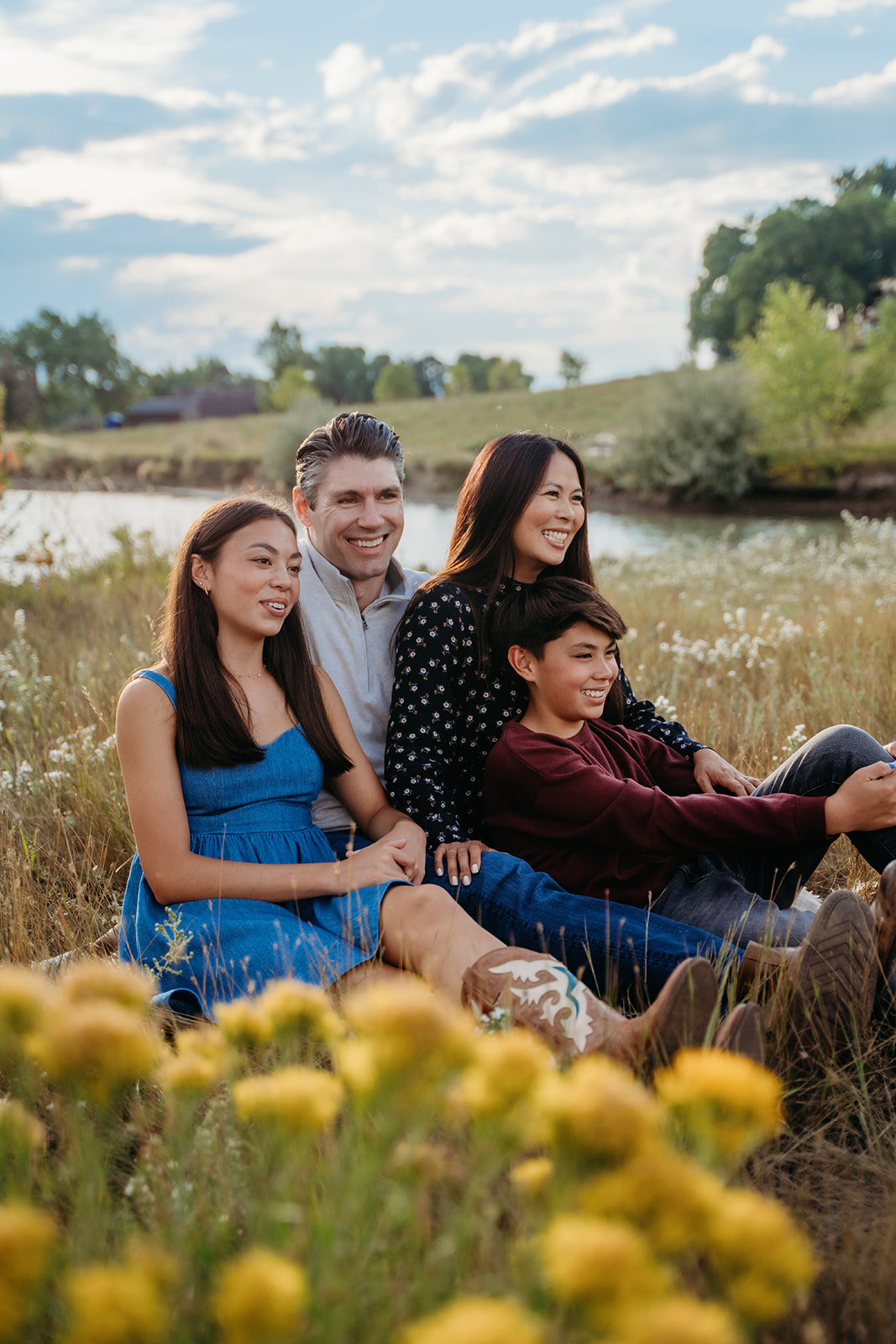 The whole family sits together on the edge of a wildflower-filled field, soaking in the last light by the water.