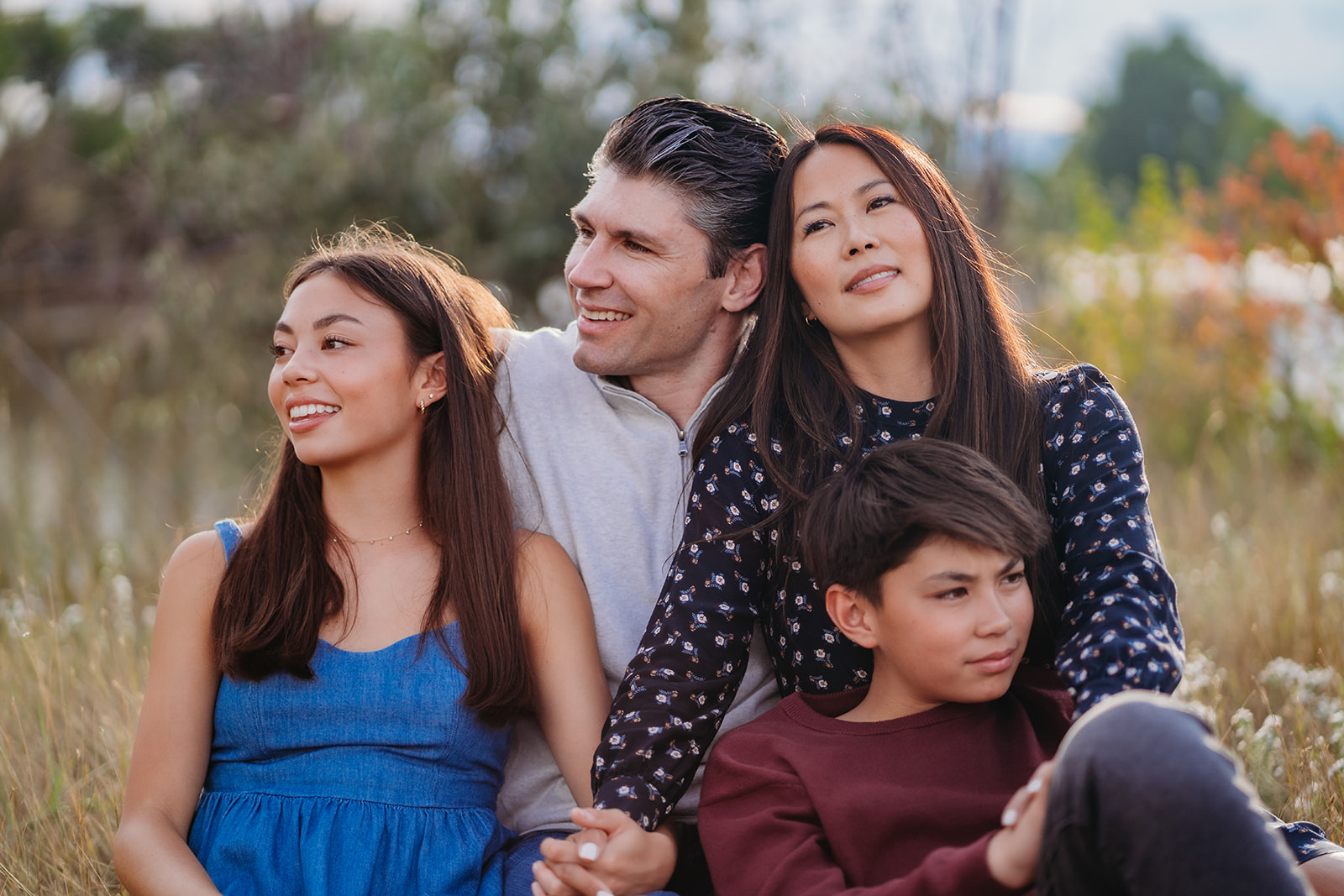 Holding hands and gazing toward the sky, this peaceful group portrait captures the essence of heartfelt family outdoor pictures.