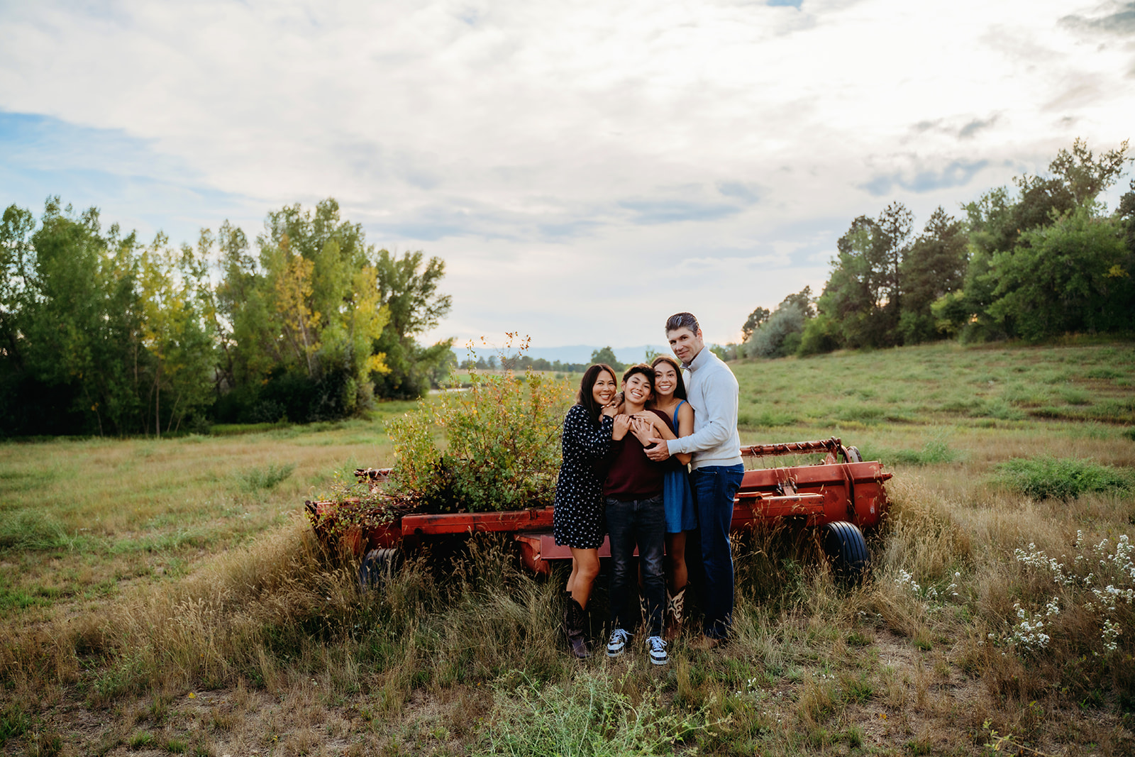 Everyone leans in for a close hug by a vintage red cart—this is the kind of warmth that defines great family outdoor pictures.