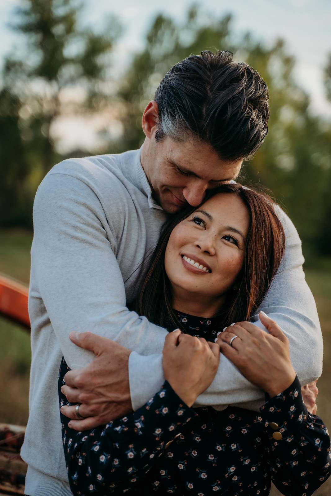 A sweet moment between parents as they embrace closely, his arms wrapped around her while she smiles up, adding quiet intimacy to their family outdoor pictures.