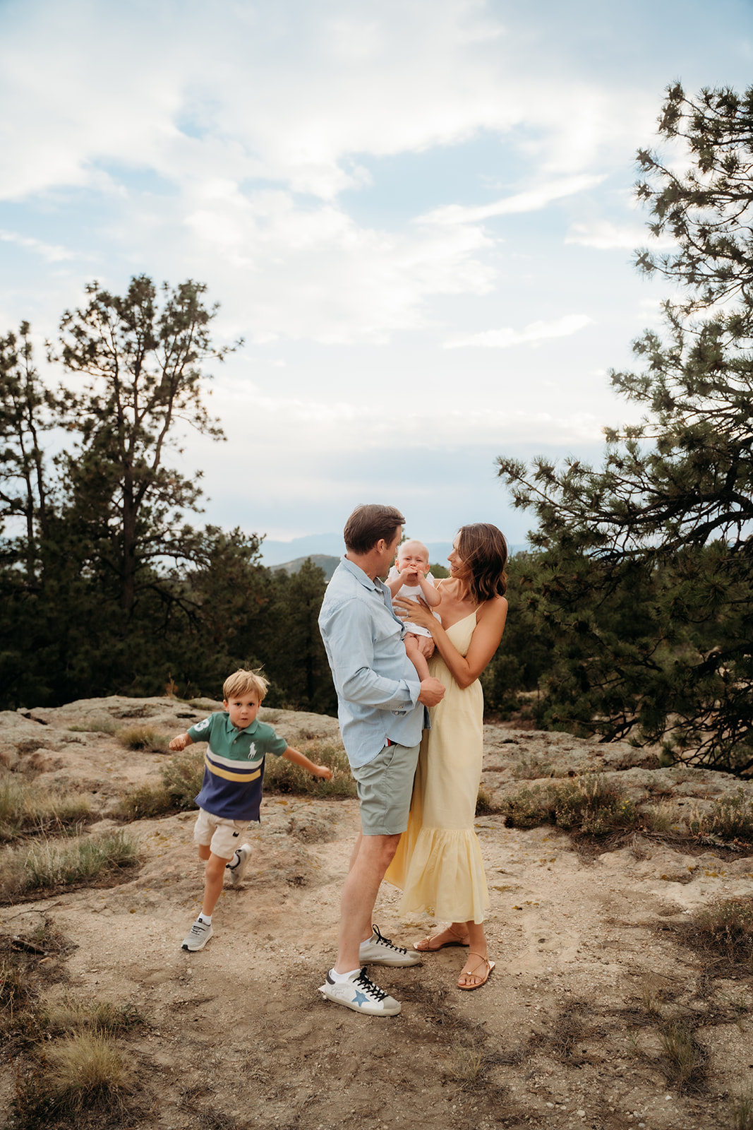 Parents holding their baby while their older son runs toward them—action shots like this are often overlooked in family photo tips.