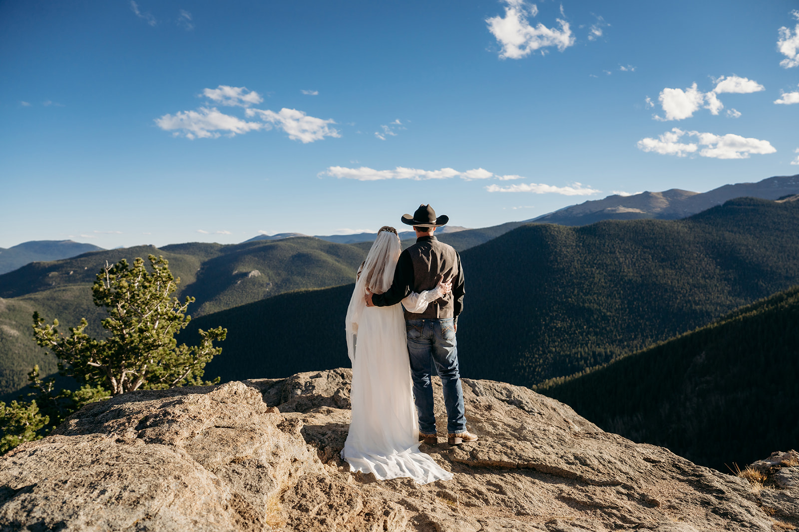 Bride and groom in cowboy hat embrace while overlooking vast Colorado mountain views, a moment full of love and inspiration for how to write vows.
