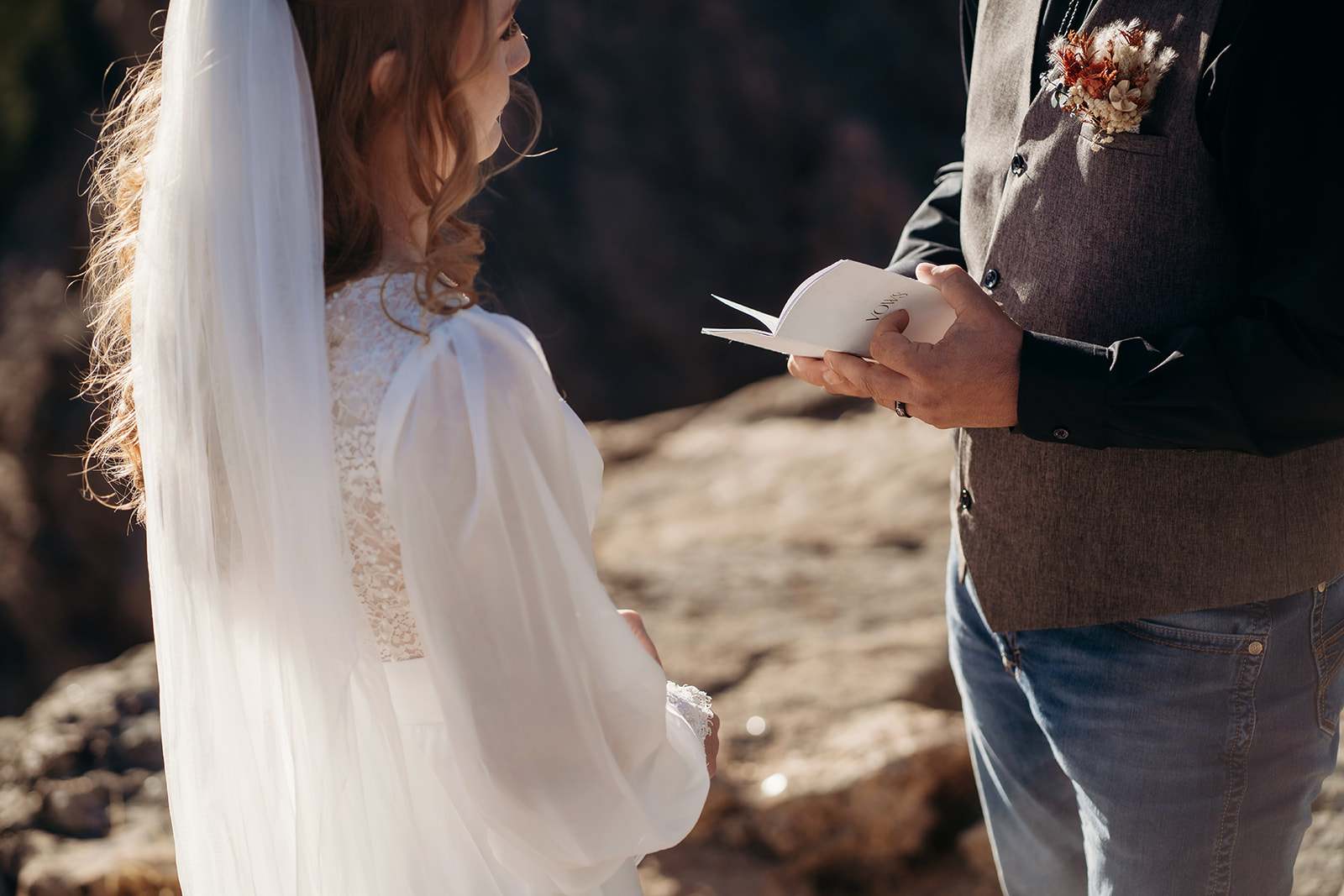 Groom reads heartfelt vows from a small vow book as bride listens, a tender example of how to write vows with intention and love.