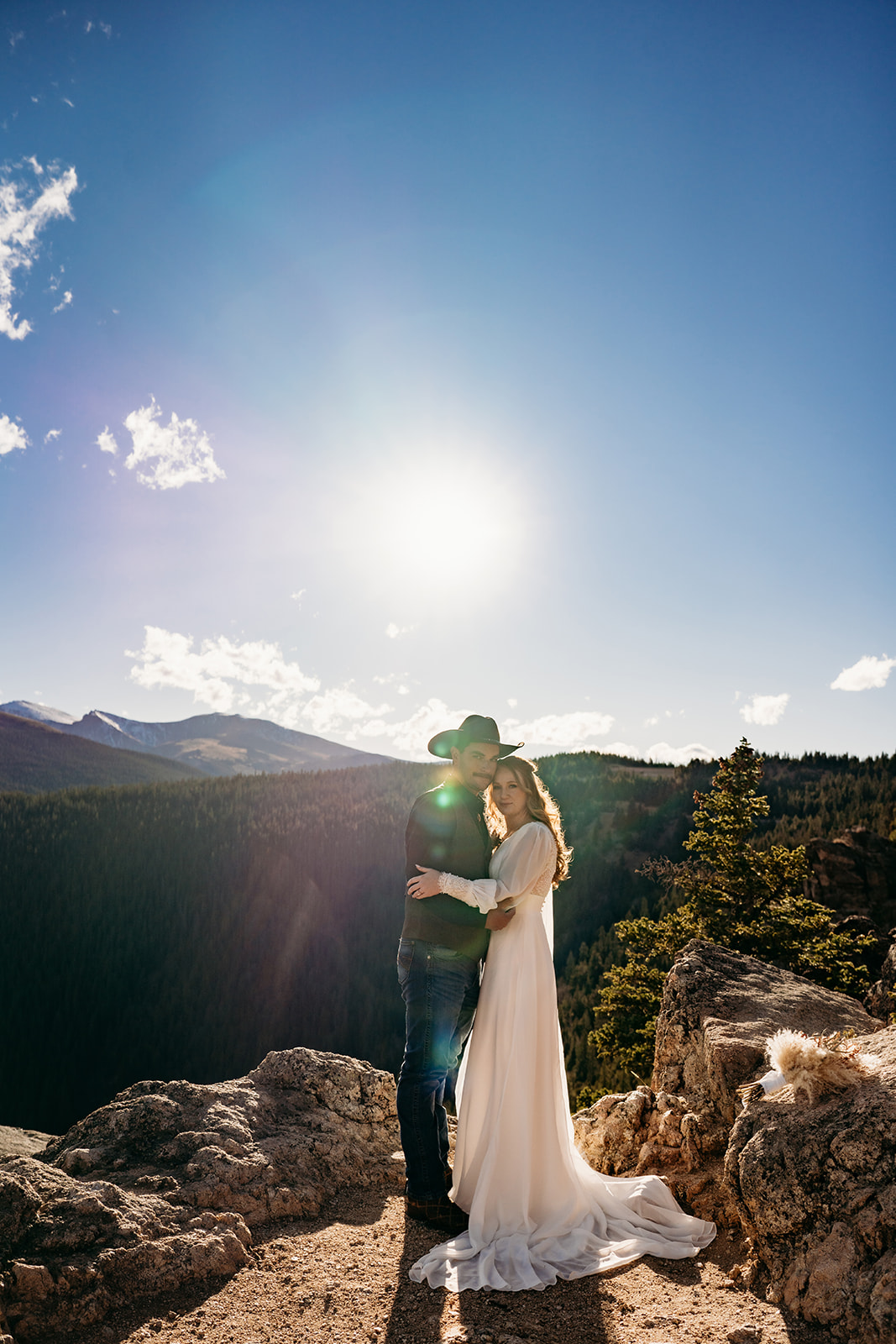 Bride and groom wrapped in each other’s arms at sunset, surrounded by mountain views and golden light.
