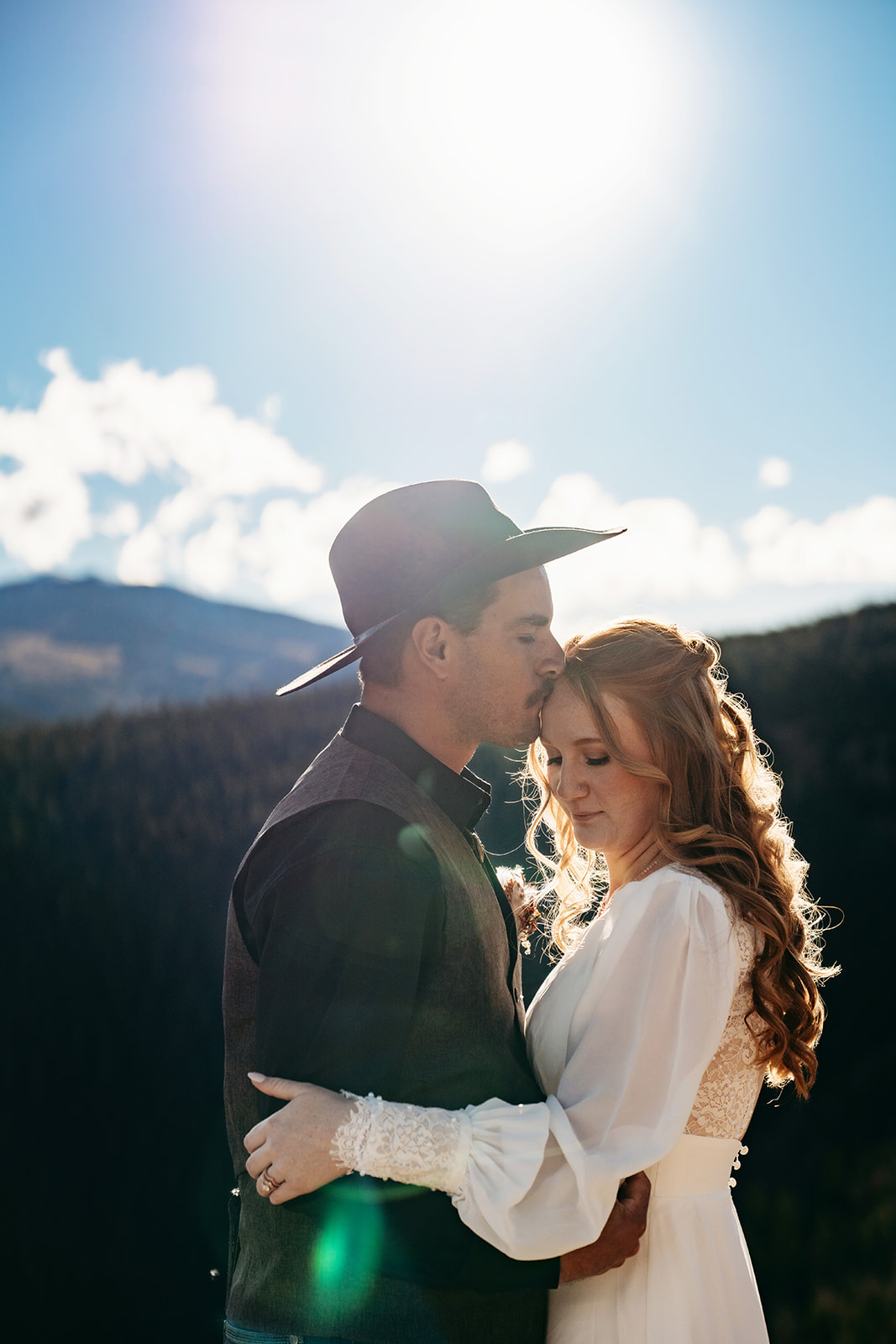 Groom kisses bride’s forehead as they embrace, glowing in the warmth of the sun and the joy of vows they wrote with intention.