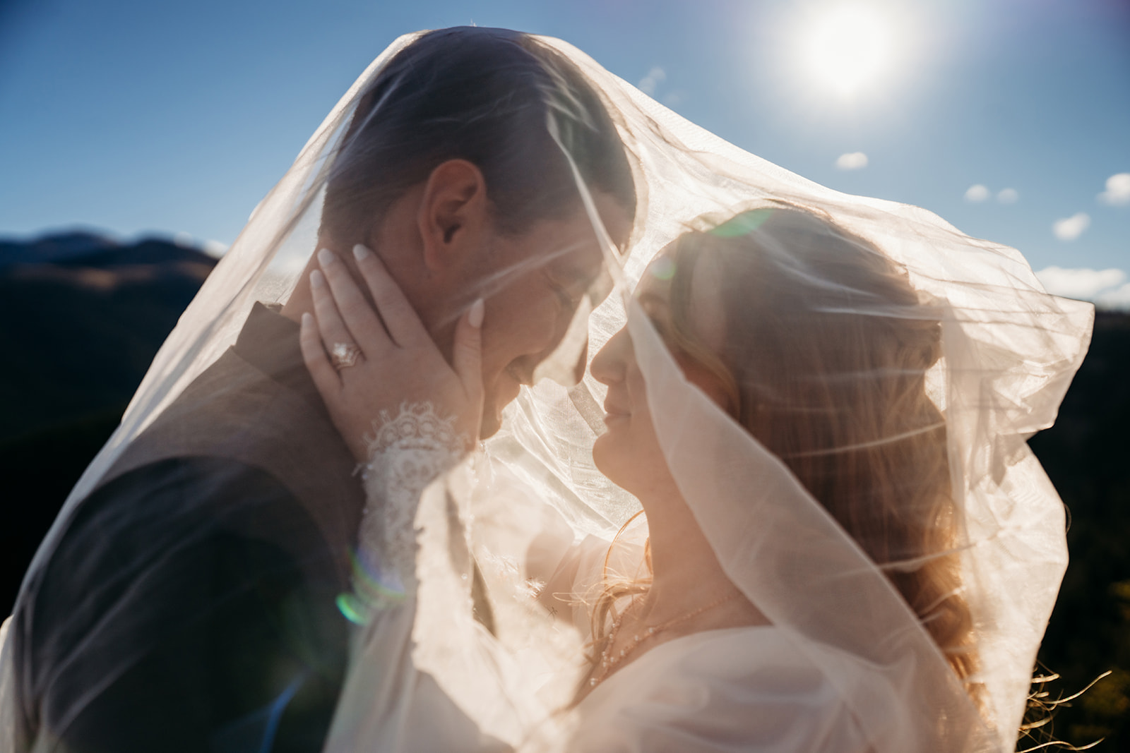 Bride and groom forehead to forehead under her veil, smiling in the sun, a private moment after sharing personal vows they wrote themselves.