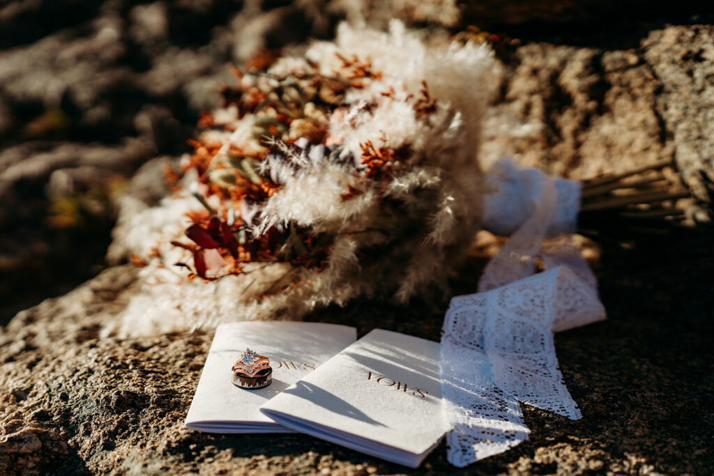 Flat lay of wedding bouquet and vow books on Colorado granite, a beautiful visual of how to write vows that are as meaningful as they are memorable.