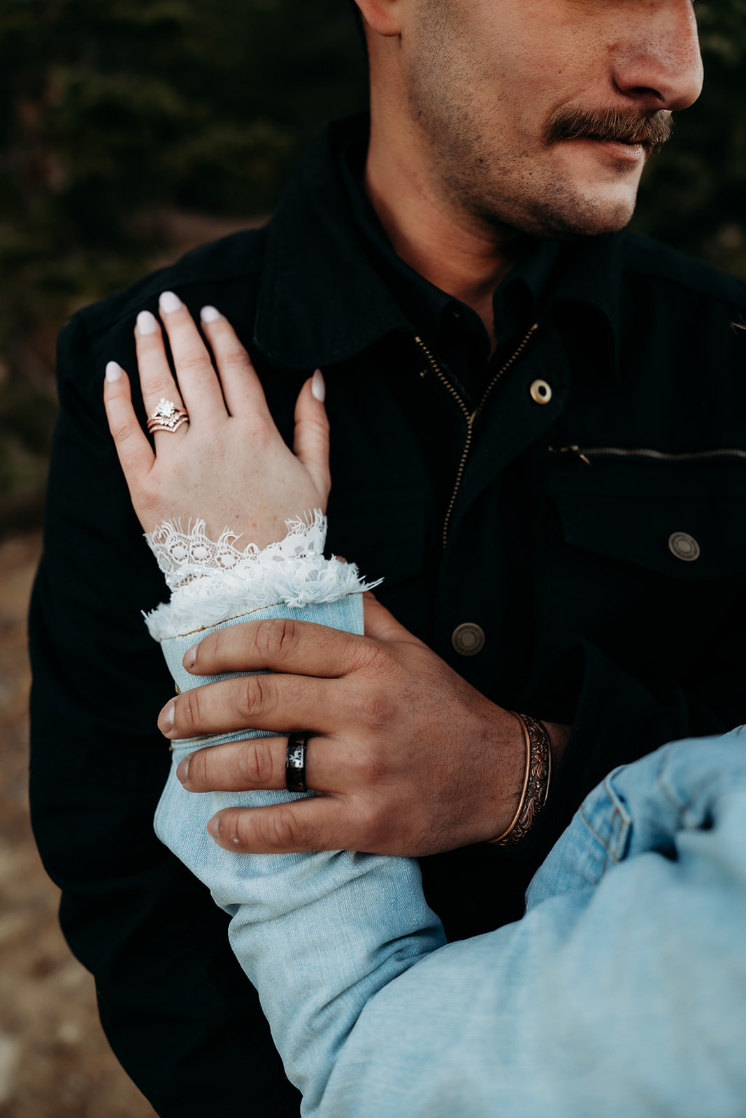 Detail shot of bride’s hand with lace cuff resting on groom’s arm, showing off wedding rings after their vows were spoken.