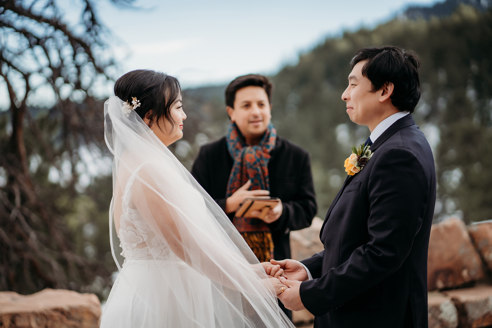 Emotional moment as bride and groom hold hands during their Colorado winter wedding vows.
