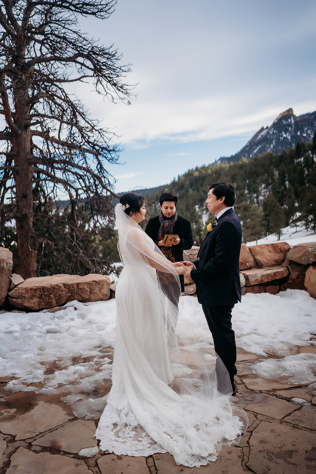 Couple exchanging vows on a snow-covered patio during their Colorado winter wedding.