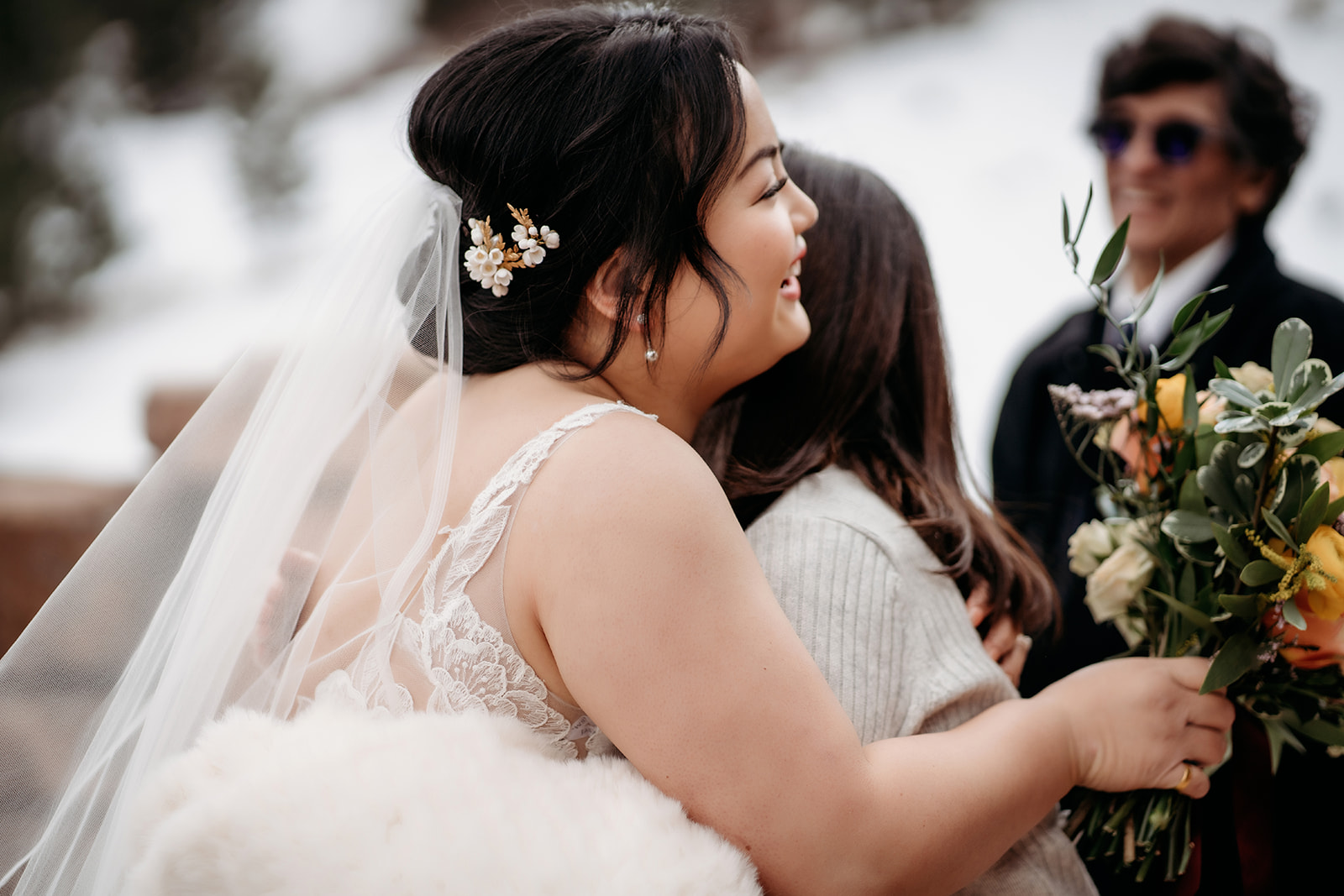 Bride hugging a guest with a bouquet in hand, joy radiating during the celebration.
