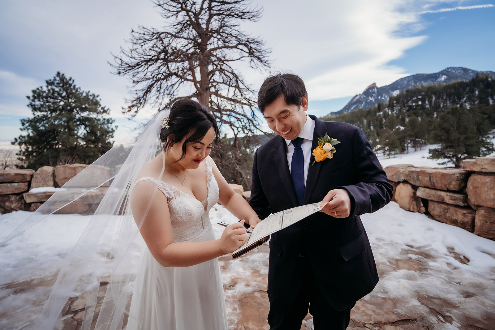 Couple signing their marriage license with joyful smiles at their snowy Colorado winter wedding.