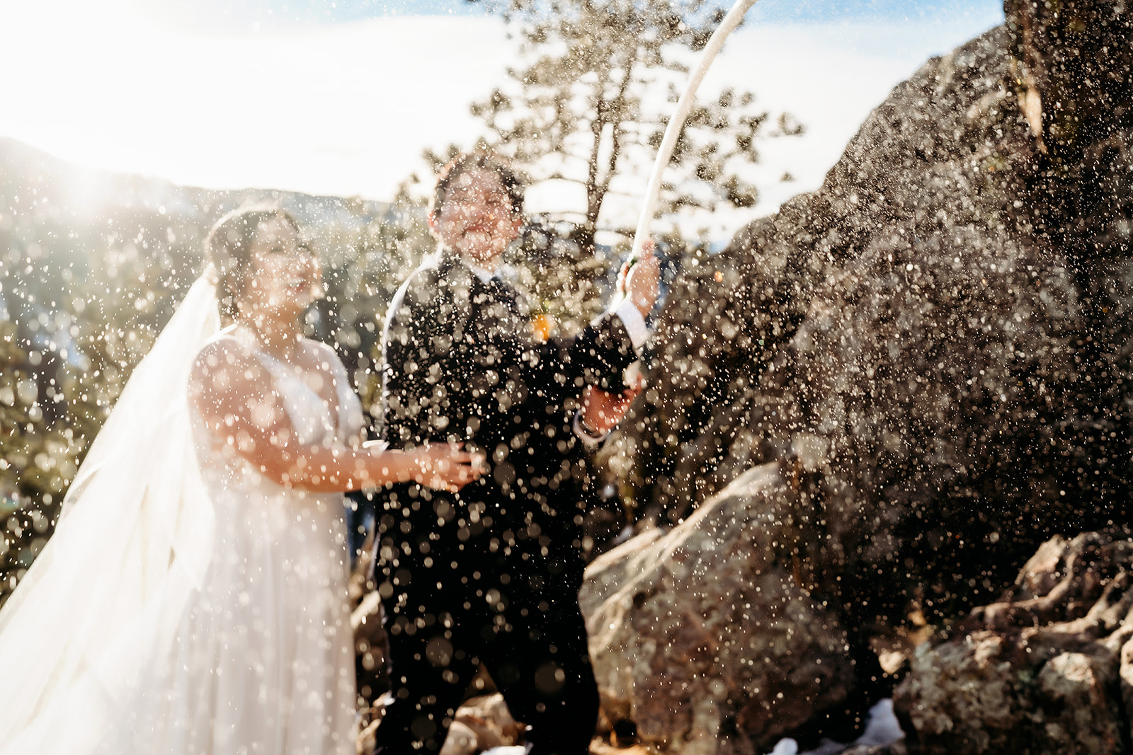 Champagne spray fills the air as the couple celebrates in the snowy mountains of Colorado.