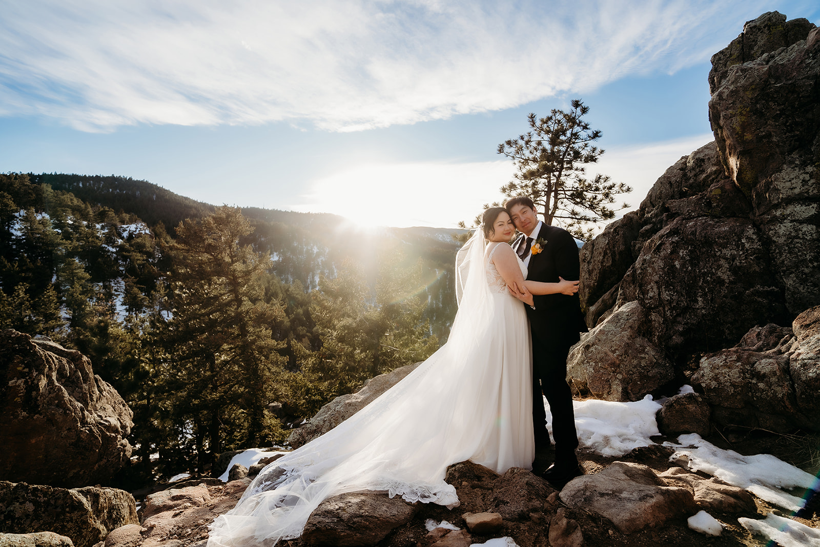 Couple poses together on a rocky overlook with sweeping Colorado views and golden winter light.