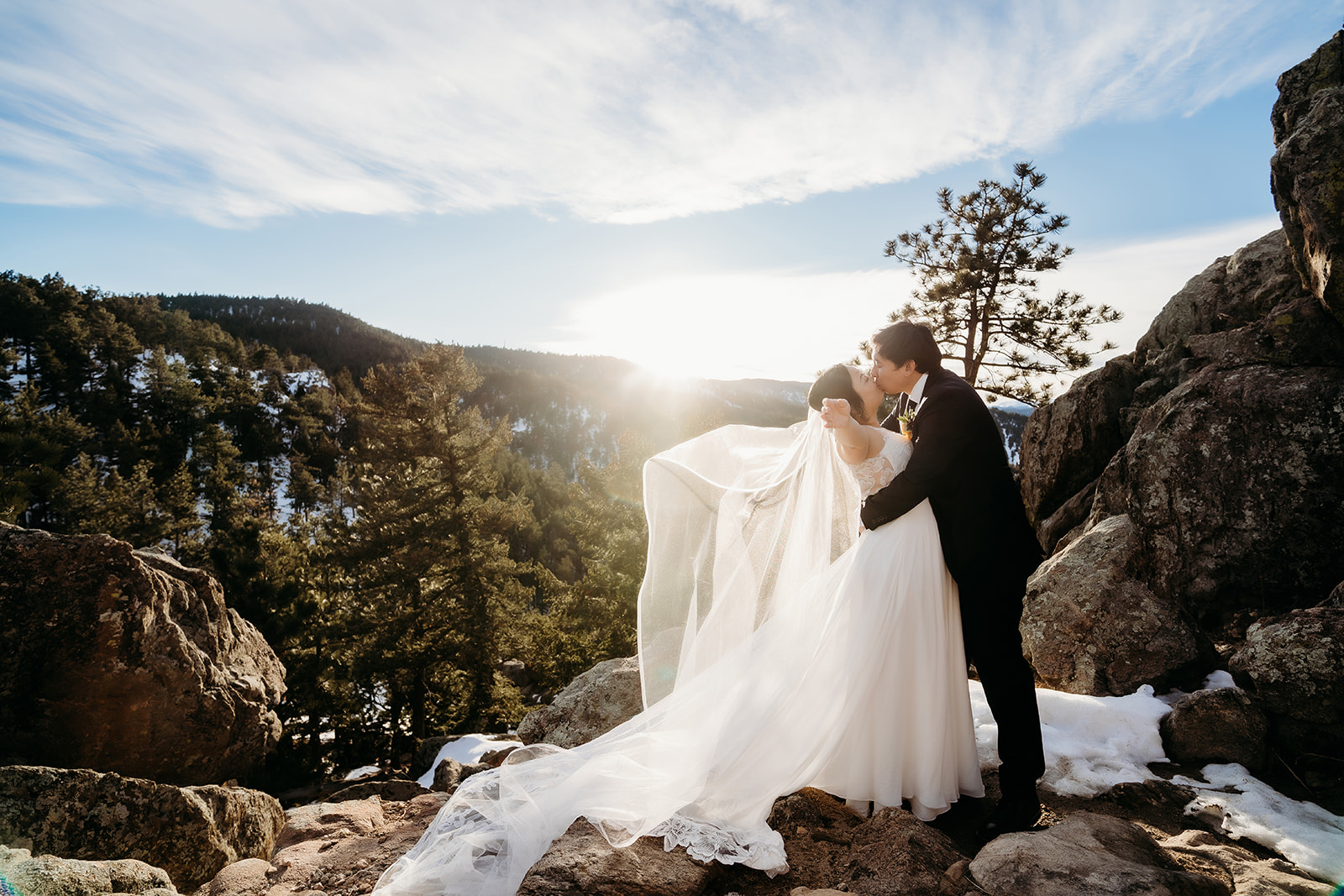 A sweet kiss as the bride’s veil catches the breeze during a Colorado winter wedding celebration.