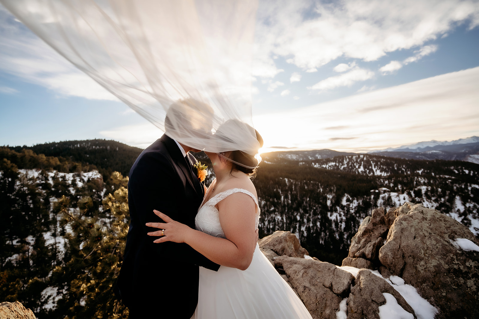 Bride’s veil catches the light mid-kiss on a mountaintop at their Colorado winter wedding