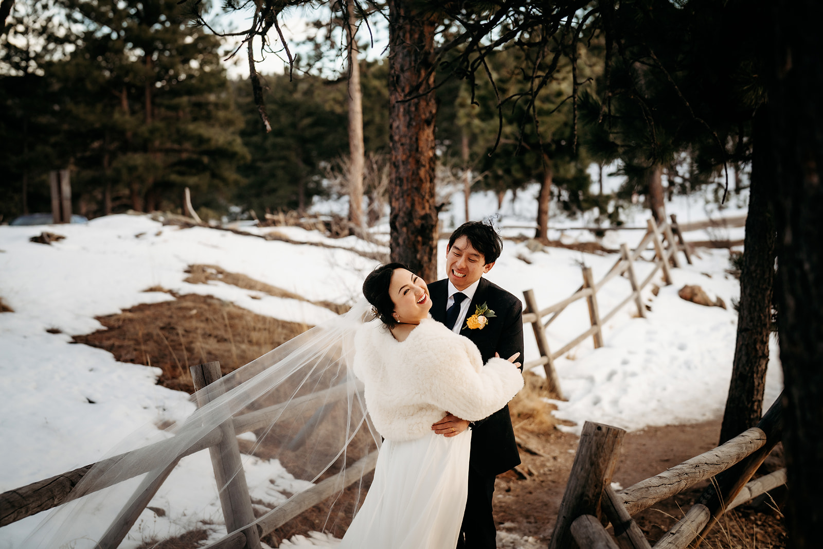 Groom twirls bride on a snow-dusted path, laughter filling the air during their Colorado winter wedding.