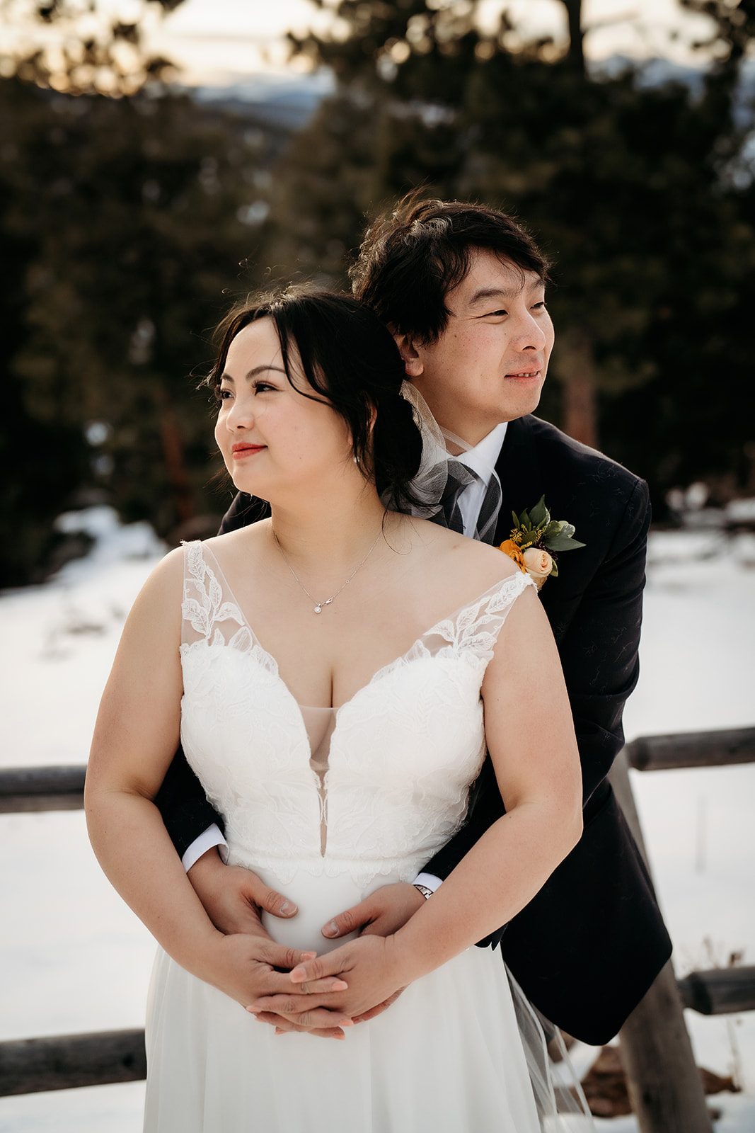 Bride and groom embrace with a snowy forest backdrop at their Colorado winter wedding.