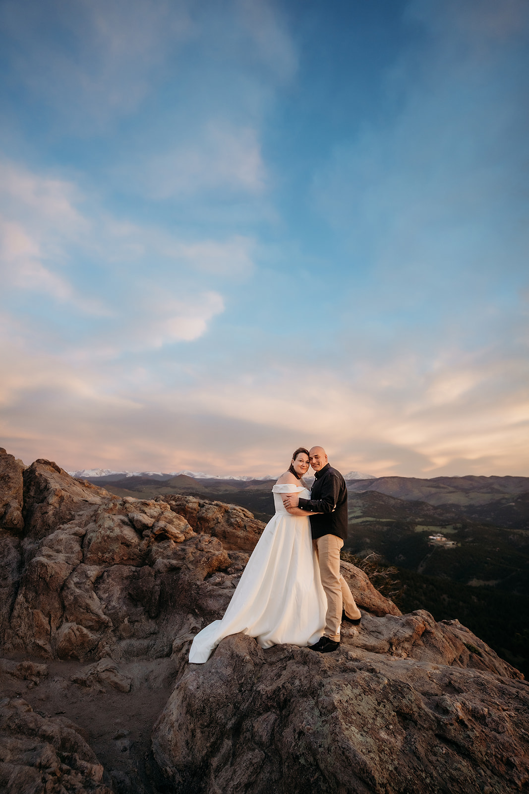 Cuddled close on a rocky ridge, the couple embraces as Colorado’s endless mountains stretch out behind them.