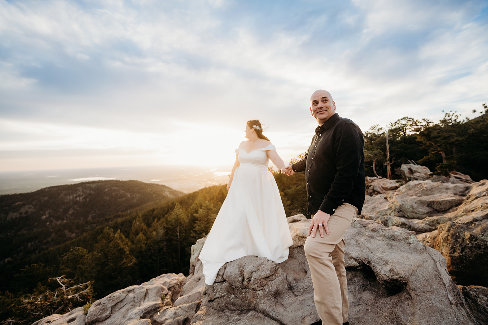 Hand in hand on the rocks, the couple takes in the sunset together—joyfully captured by their elopement photographer in Colorado.