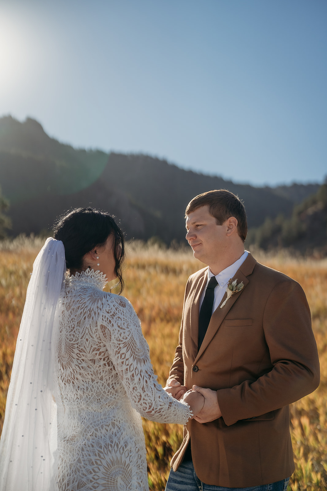 Holding hands and exchanging vows, the couple stands in a glowing field with the Flatirons rising behind them in classic Colorado style.
