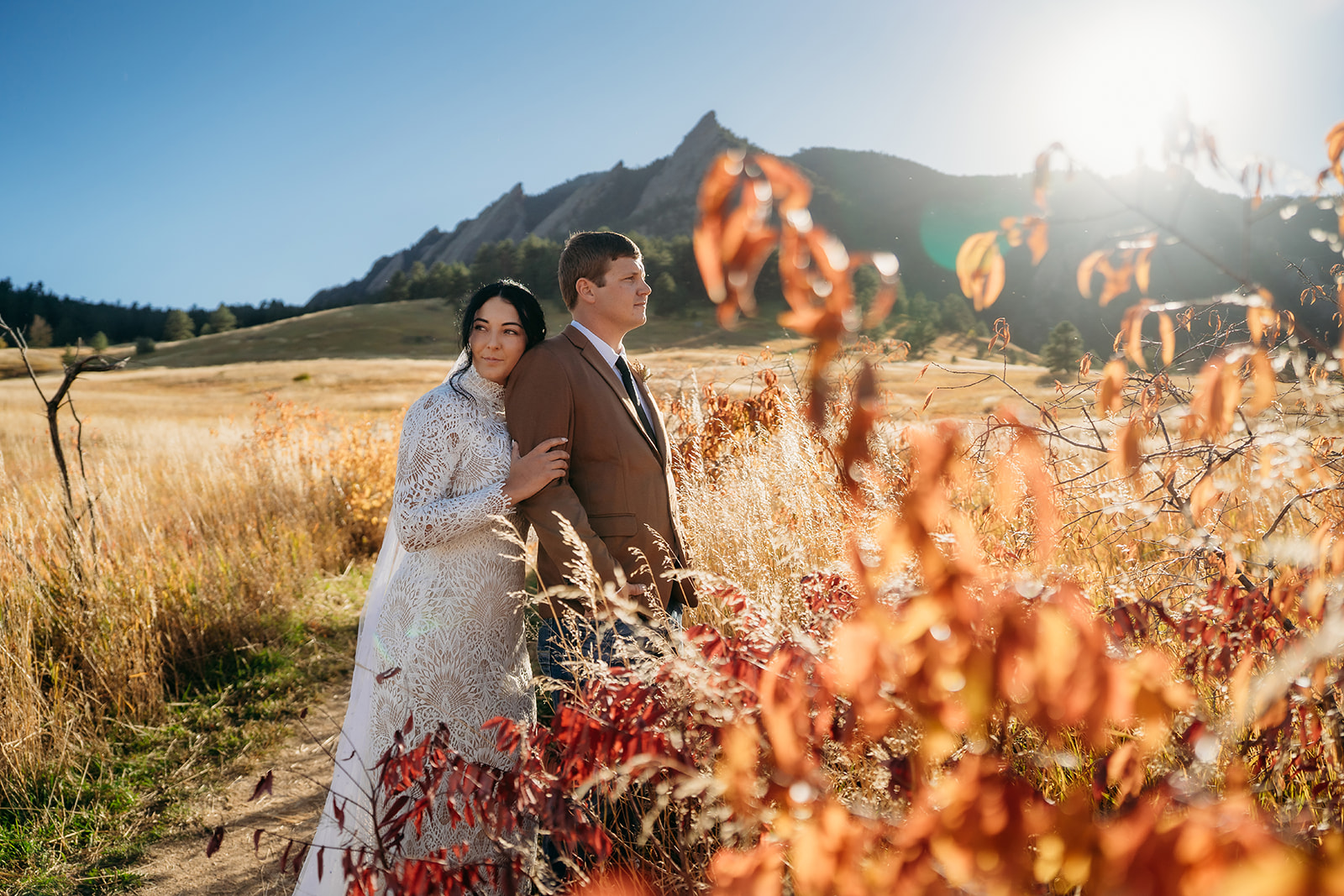 Bride and groom nestled in golden fall foliage with the Flatirons behind them, soaking in the peacefulness of their Boulder elopement.