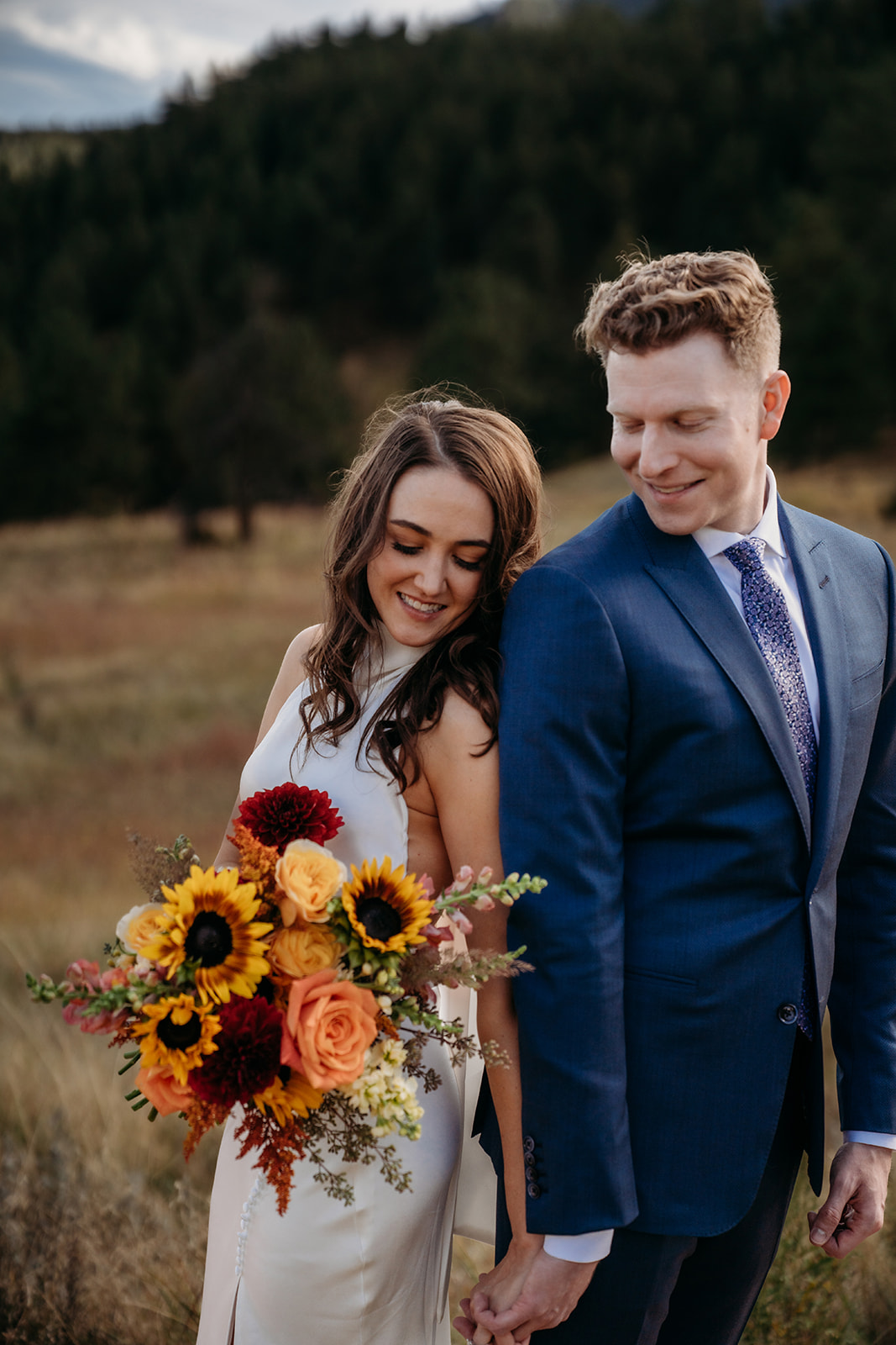 Newly married couple leaning against one another and smiling together after Colorado weddings ceremony. 
