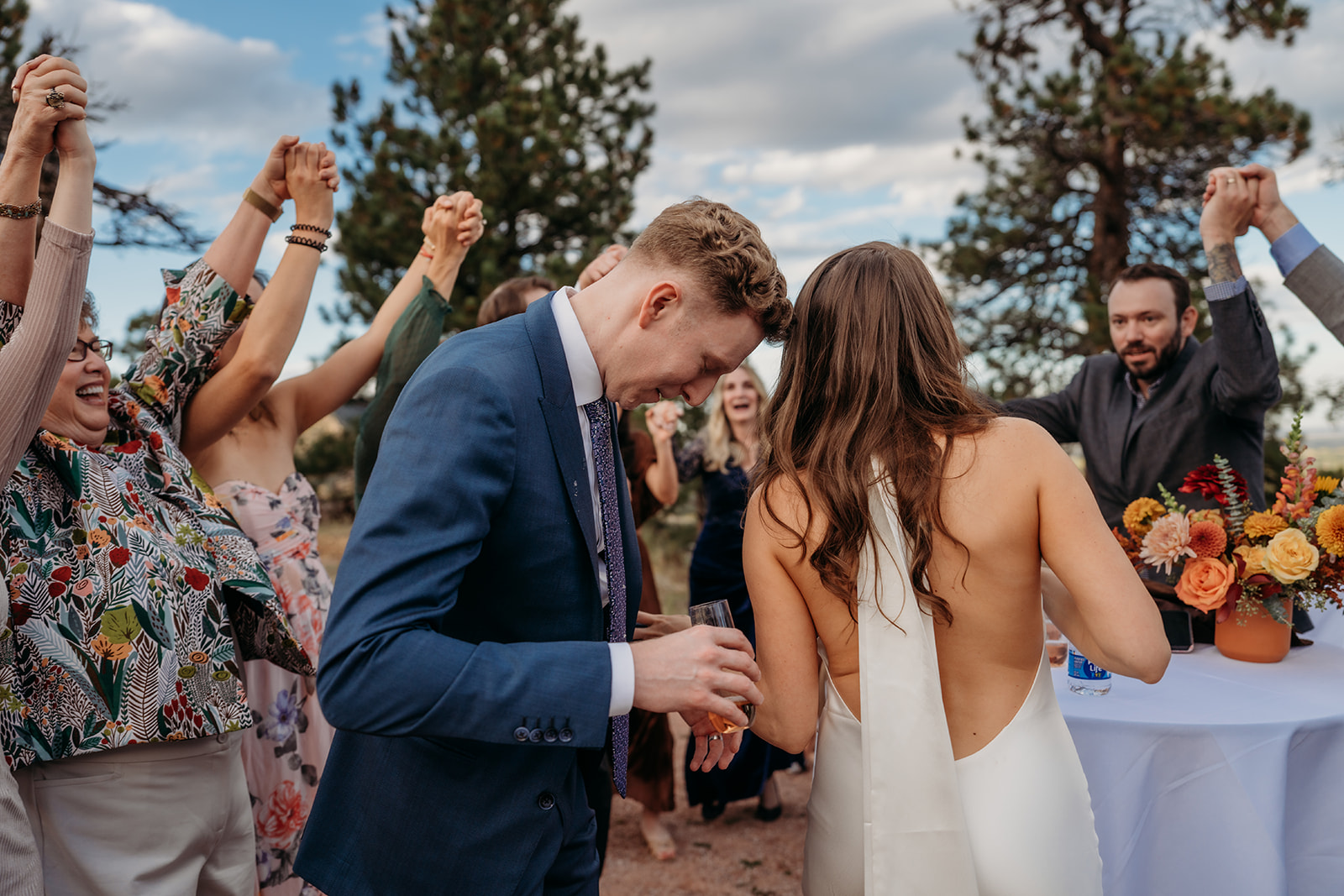 Wedding guests dancing and cheering around the couple outdoors, capturing the joyful energy of a Colorado wedding celebration.