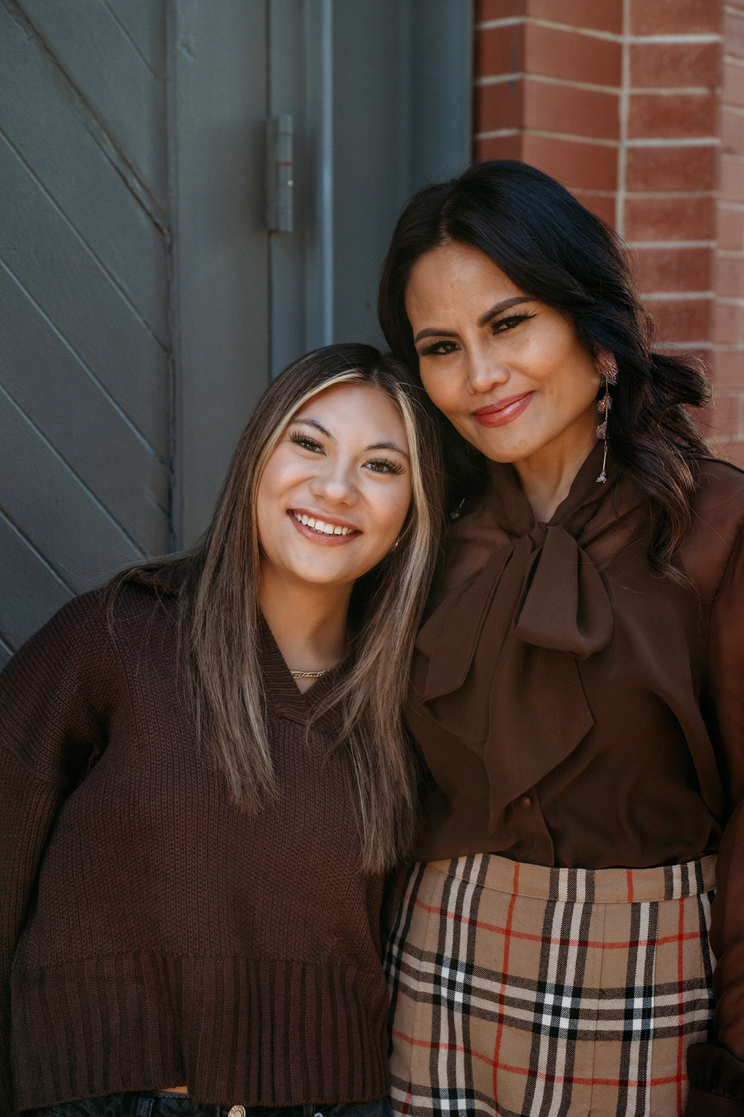 A mother and daughter leaning together and smiling during a candid family portrait session with Denver photographers in downtown Denver.