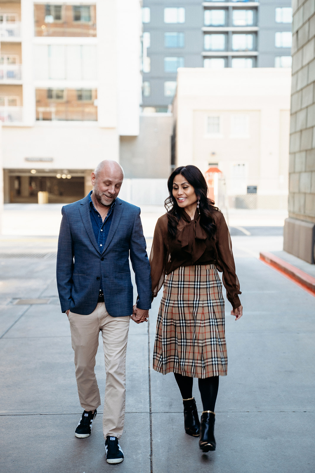 A couple walking hand in hand through an urban Denver alley, sharing a quiet laugh during a lifestyle couples session with Denver photographers.